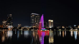 night shot of Downtown Orlando with fountain and buildings and view of water